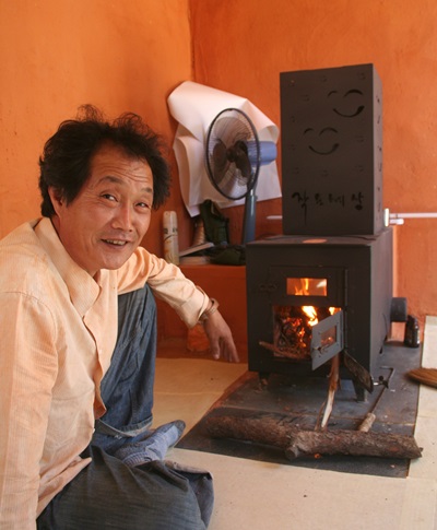 재난주택 발명가 김태경 대표가 자신이 개발한 미소난로 앞에서 불을 쬐고 있다.