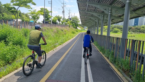 태양광 패널이 지붕 역할을 해서 그늘이 생긴 자전거 도로에서 자전거를 타는 안산 주민들. 사진= 이재표 기자